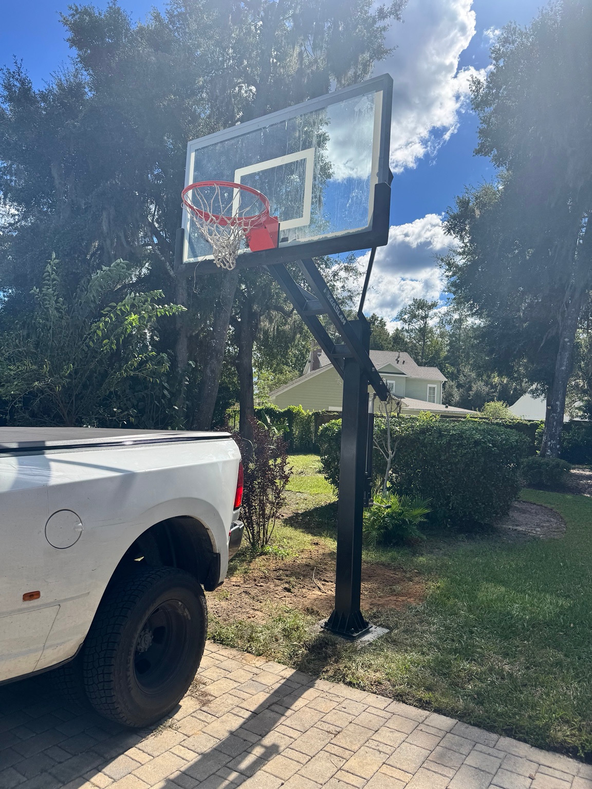 Installed in-ground basketball hoop beside a paved driveway