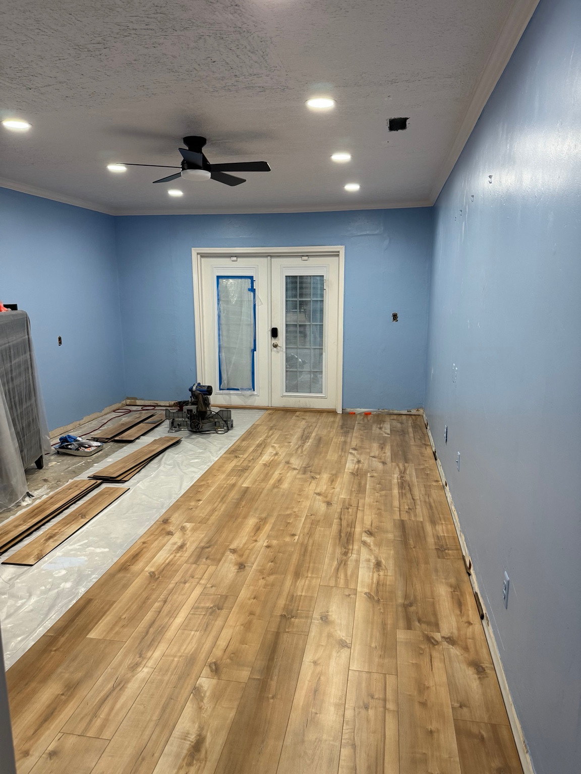 Wood-look plank flooring being installed in a room, with tools and materials visible
