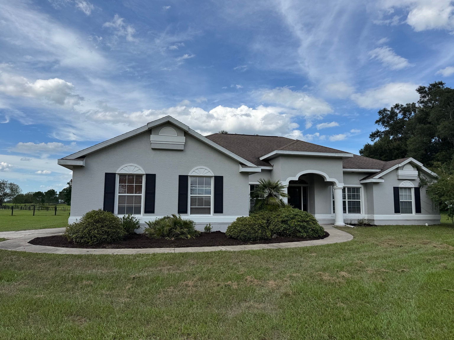 Fresh dark mulch around shrubs along the curved front walkway of a home